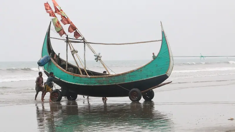 সমুদ্রসৈকতের ভেজা বালিতে রাখা সবুজ রঙের একটি কাঠের নৌকা