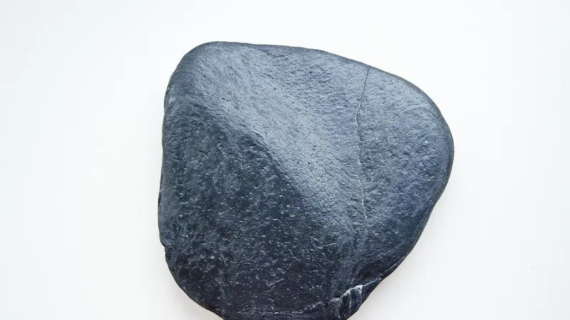 সাদা পটভূমিতে রাখা মসৃণ একটি কালো পাথর