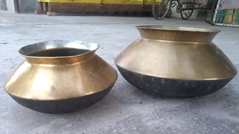 সিমেন্টের মেঝেতে পাশাপাশি রাখা পিতলের দুটি হাঁড়ি