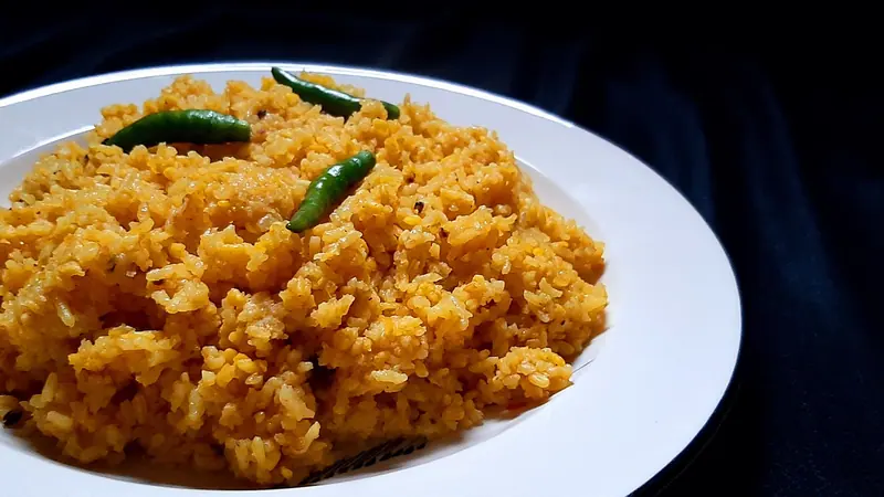 সাদা প্লেটে কাঁচা মরিচ দিয়ে সাজানো ভুনা খিচুড়ি