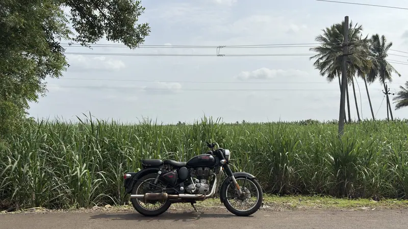আখক্ষেত আর তালগাছের পাশে গ্রামের রাস্তার ধারে দাঁড় করানো একটি মোটরসাইকেল