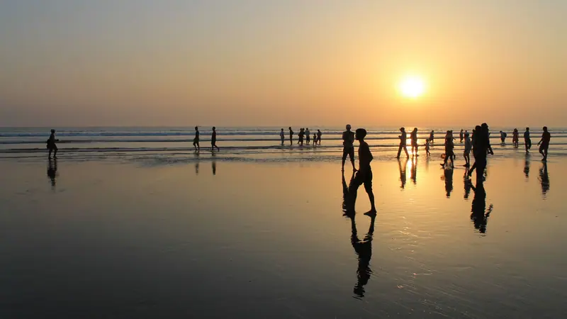 সূর্যাস্তের সময় সমুদ্রসৈকতে হাঁটতে থাকা মানুষের ছায়ামূর্তি