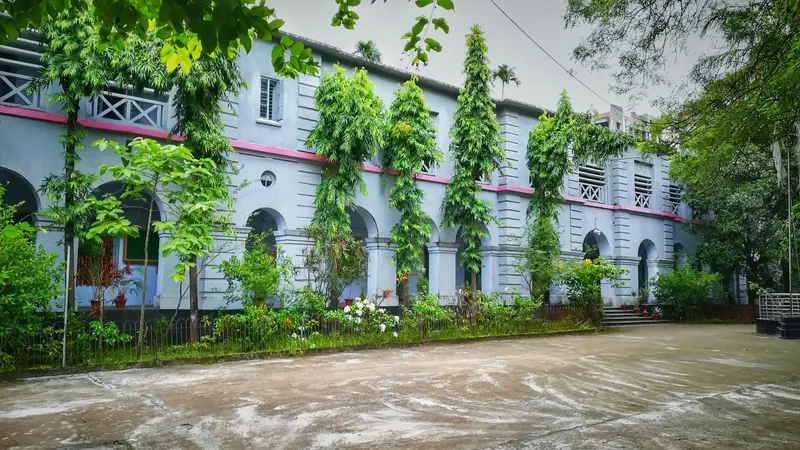 গাছপালায় ঘেরা পুরনো একটি স্কুল ভবন, সামনে খোলা মাঠ